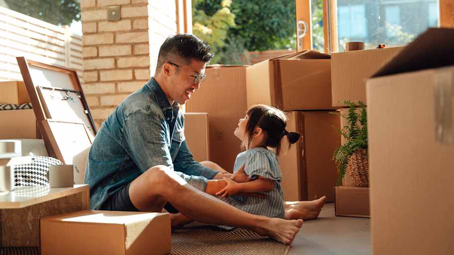 Father and daughter sitting on the floor surrounded by cardboard boxes 